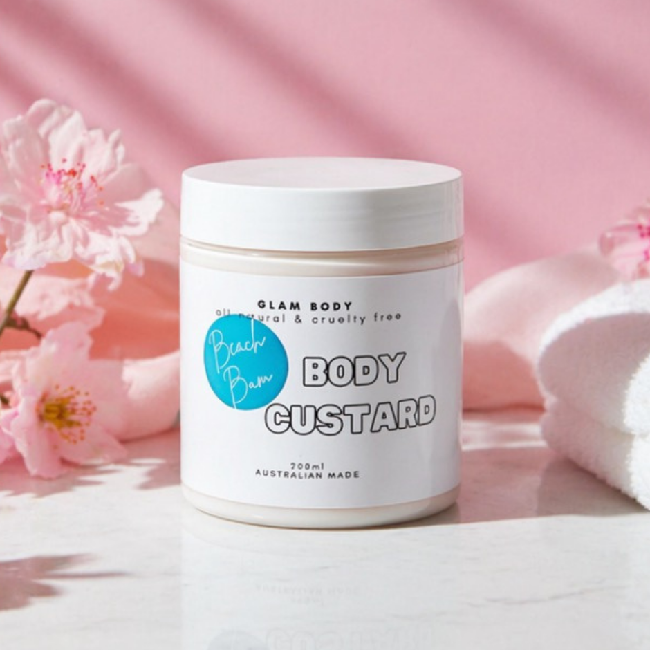 Jar of Glam Body Beach Bum Body Custard with pink flowers and towel in the background