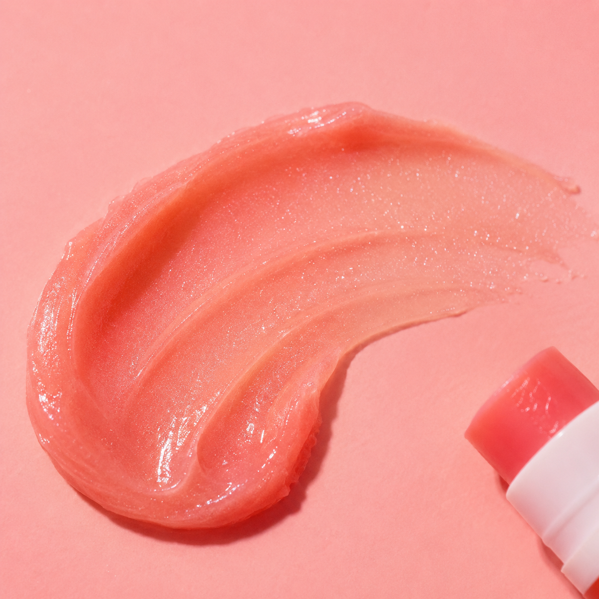 Pink lip balm with a swatch on a pink background