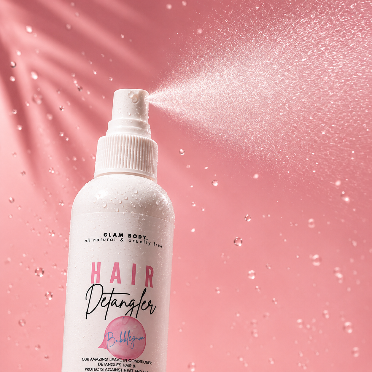 Hair detangler spray bottle with product being sprayed on a pink background