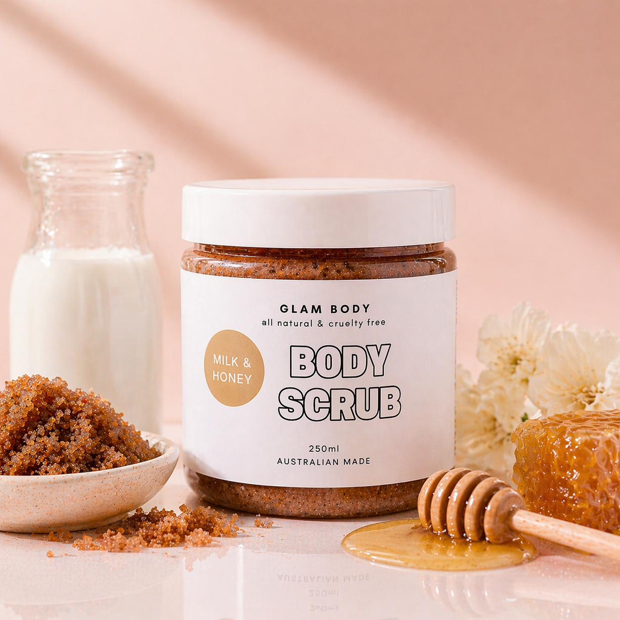 Glam Body Milk & Honey body scrub jar with ingredients on a soft pink background
