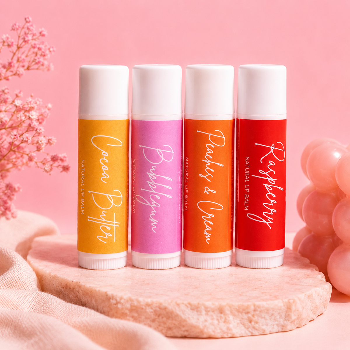 Four lip balm tubes with different flavors on a pink background