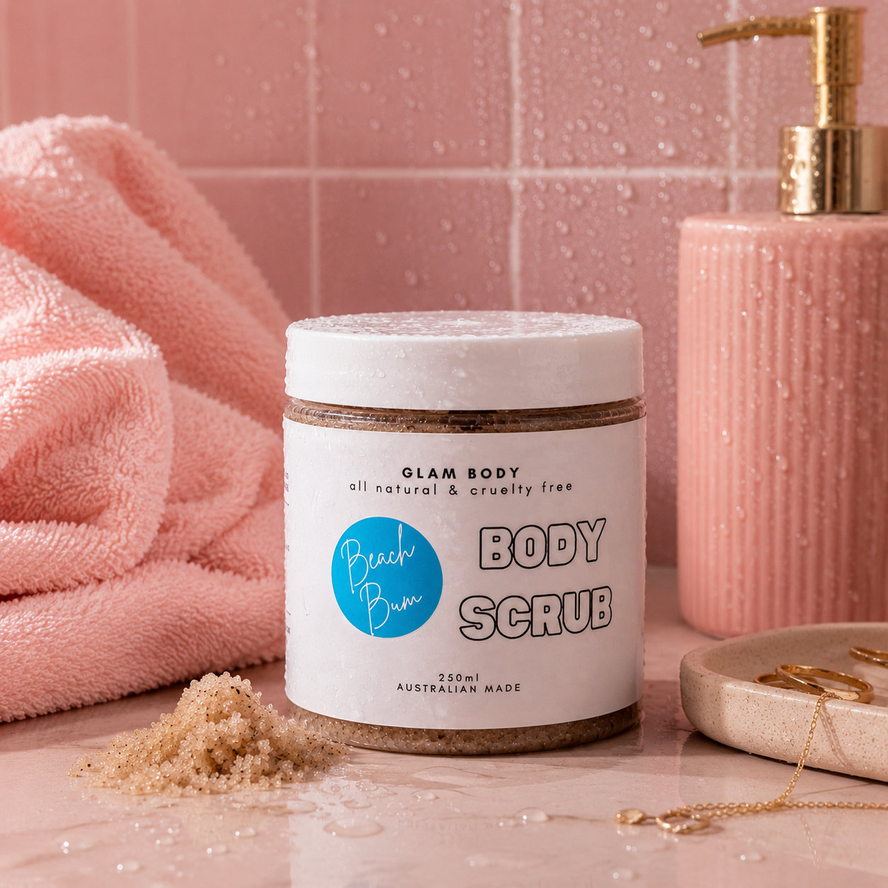 Jar of Glam Body body scrub with a pink towel and soap dispenser in the background.