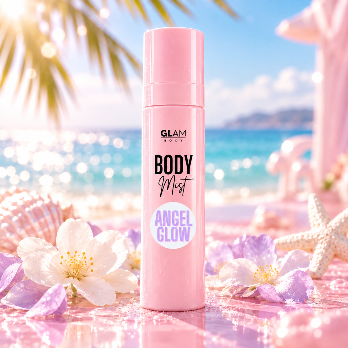 A pink cylindrical bottle of GLAM BEAUTY Body Mist Angel Glow stands on a reflective pink beach surface with tropical flowers, shells, and a blurred ocean backdrop.