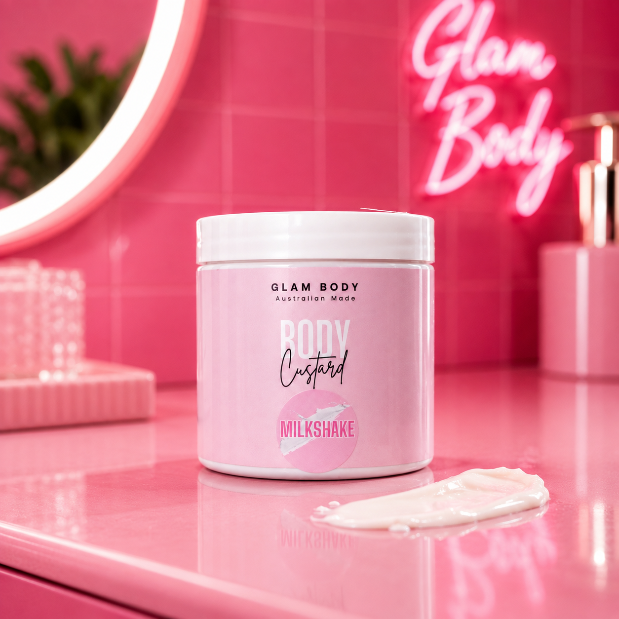 A pink cosmetic jar labeled 'GLAM BODY Australia Made Body Custard Milkshake' sits on a glossy pink surface with a dollop of cream in front. The background features a pink tiled wall, a pink neon sign reading 'Glam Body', and a pink mirror frame.