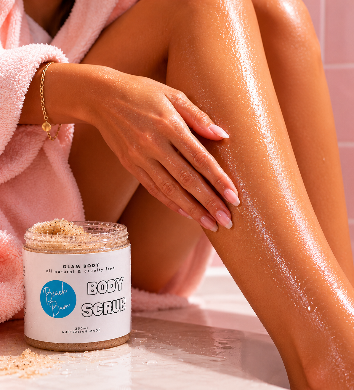 Person with smooth skin holding a jar of Beach Bum Body Scrub in a bathroom setting.