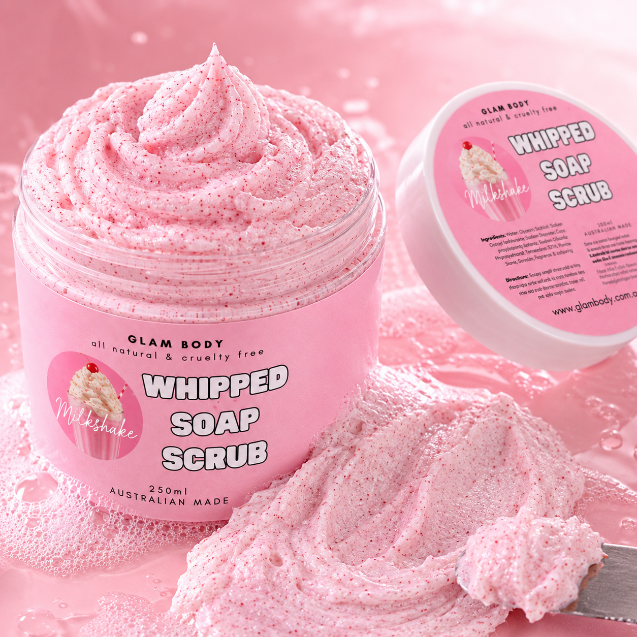 Pink whipped soap scrub in a jar with a spoonful of scrub on a pink background