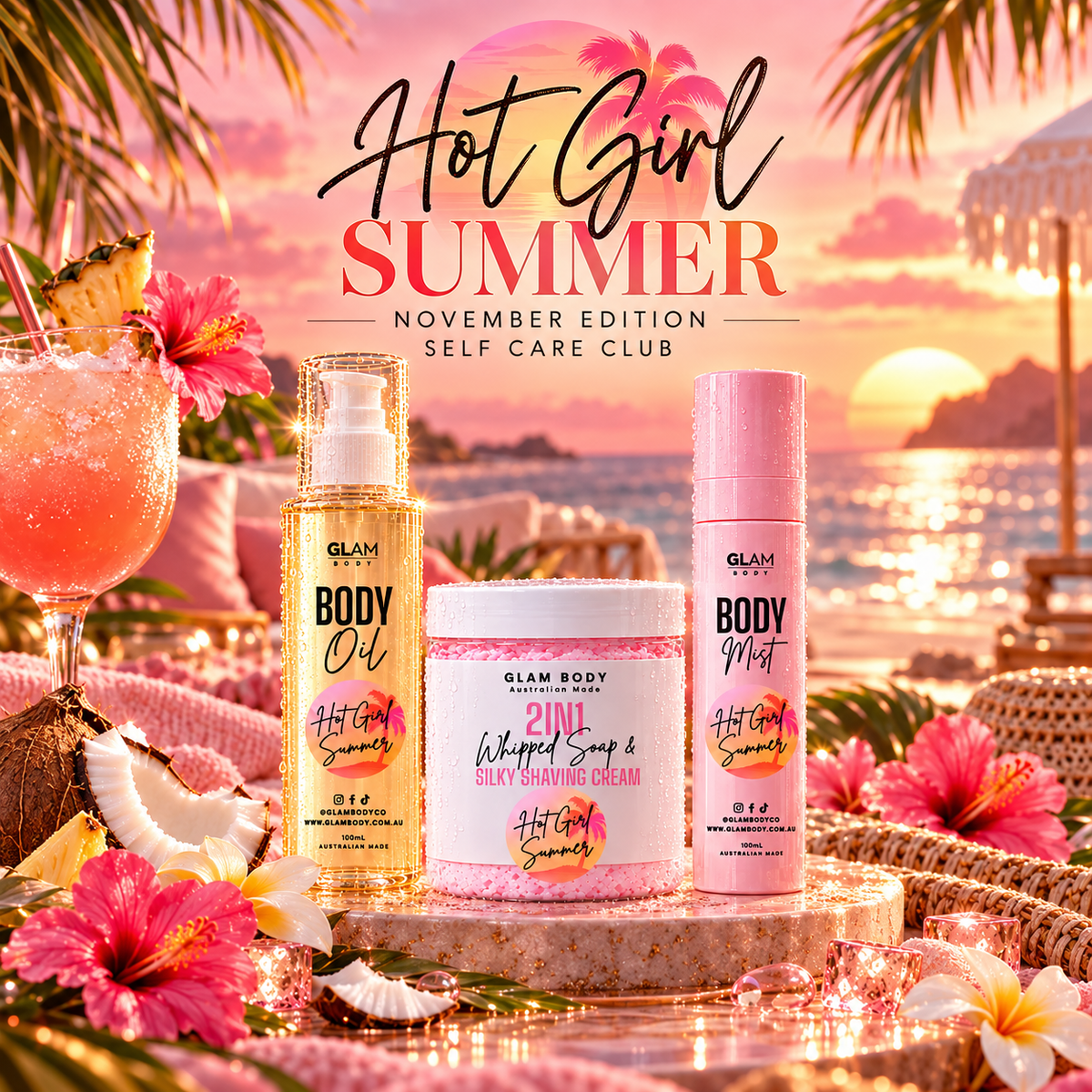 Three Glam Body Essentials self-care products are displayed on a stone tray in a tropical beach setting at sunset: a gold bottle of Body Oil, a pink bottle of Body Mist, and a white jar of Whipped Soap & Silky Shaving Cream. The scene includes a cocktail, flowers, palm leaves, and a beach backdrop, with the text 'Hot Girl Summer November Edition Self Care Club' at the top.