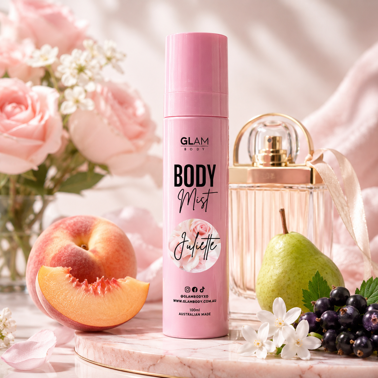 Pink 'Body Mist' spray bottle with flowers, fruit, and a glass bottle in the background.