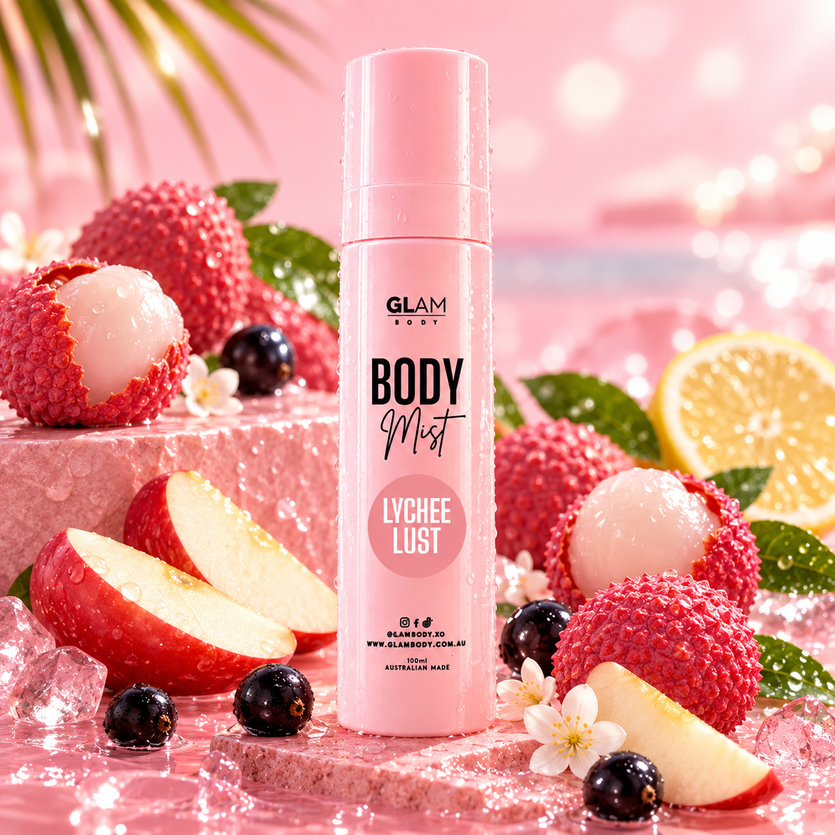 GLAM GIFT Body Mist in Lychee Lust scent, presented in a pink cylindrical bottle surrounded by fresh lychees, sliced red apples, blackberries, lemons, and ice in a pink, bubbly studio setting.