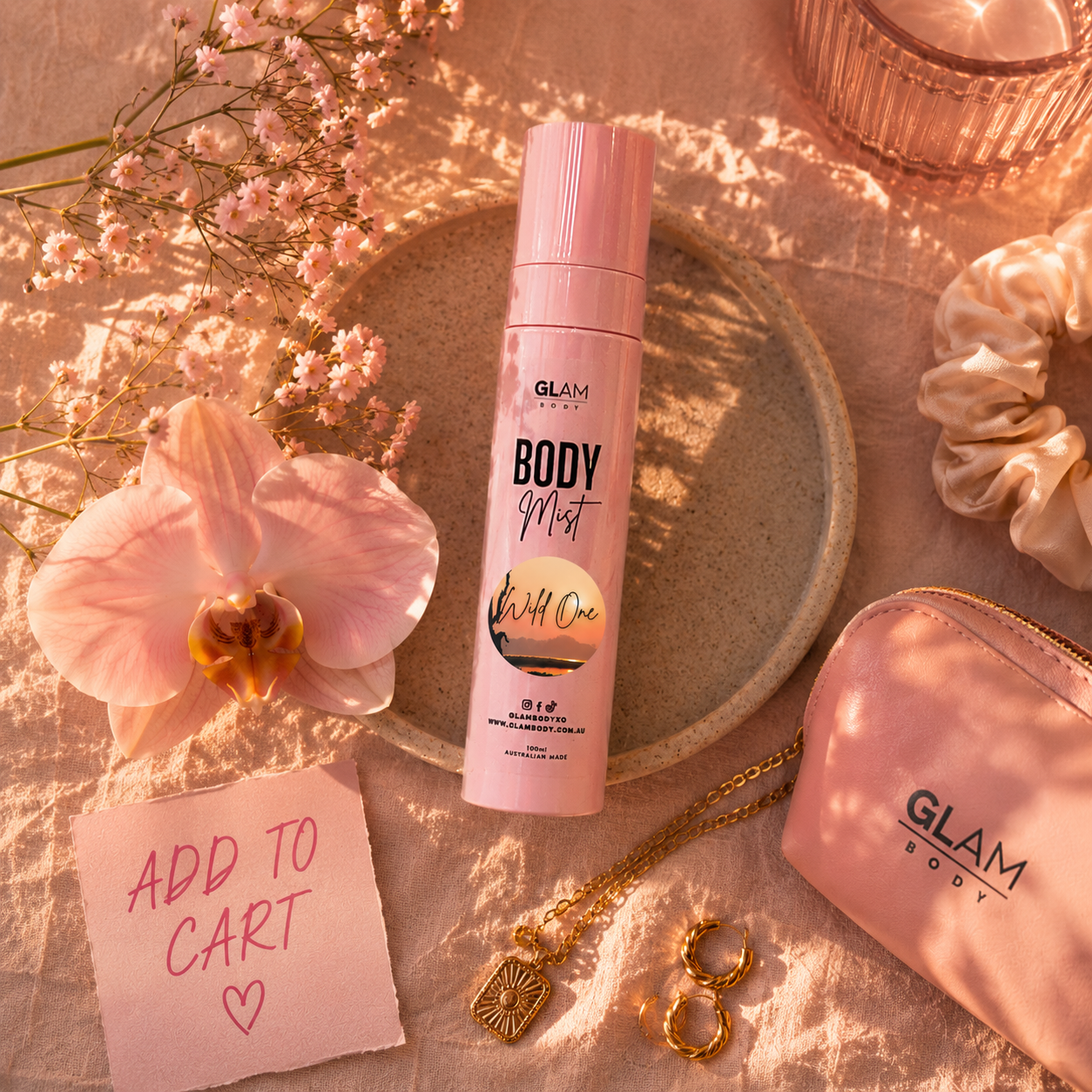 Pink 'Glam Body' body mist bottle with accessories on a decorative surface